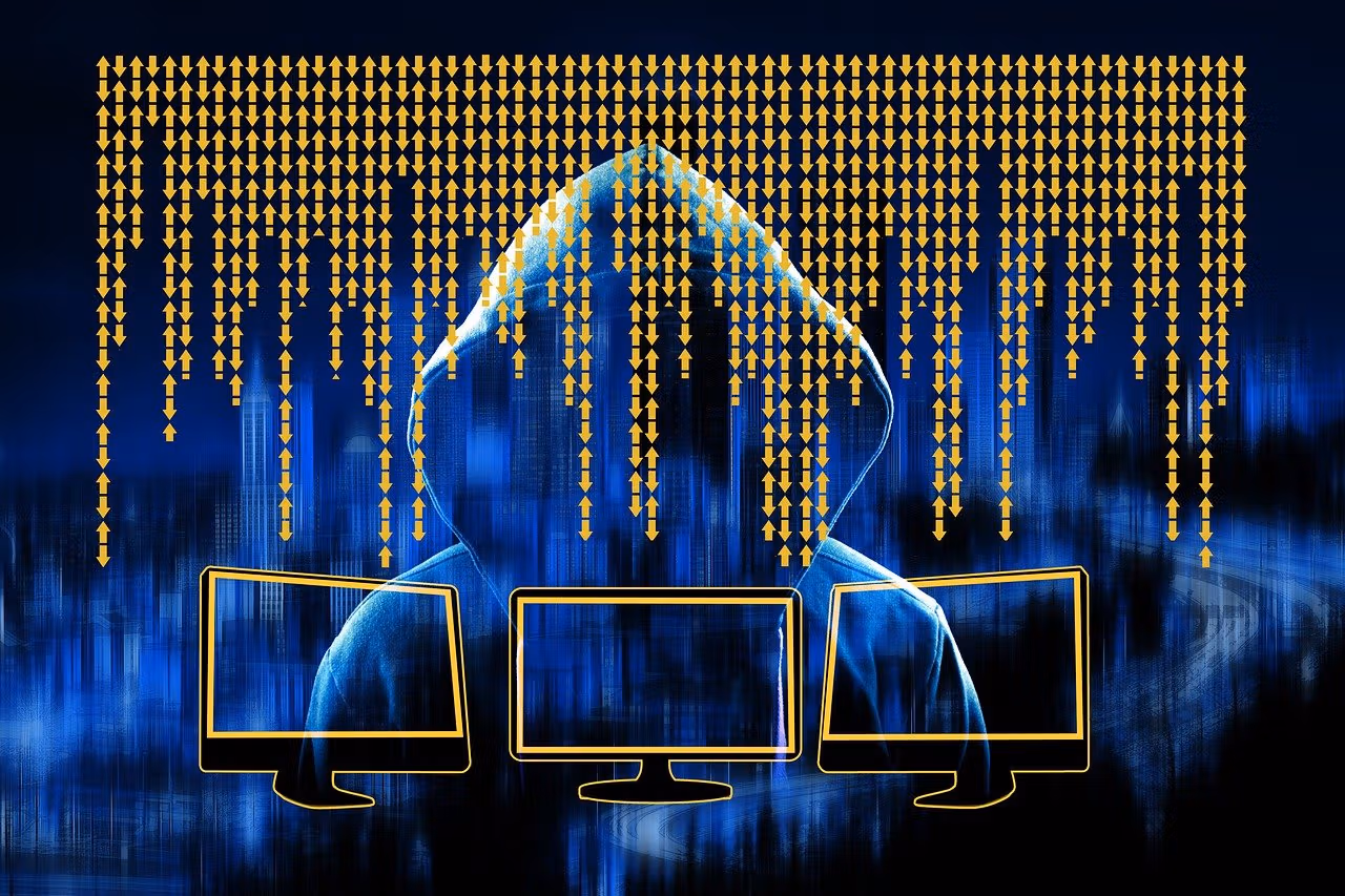 Silhouette image of a hooded figure behind three screens. (geralt/Pixabay)