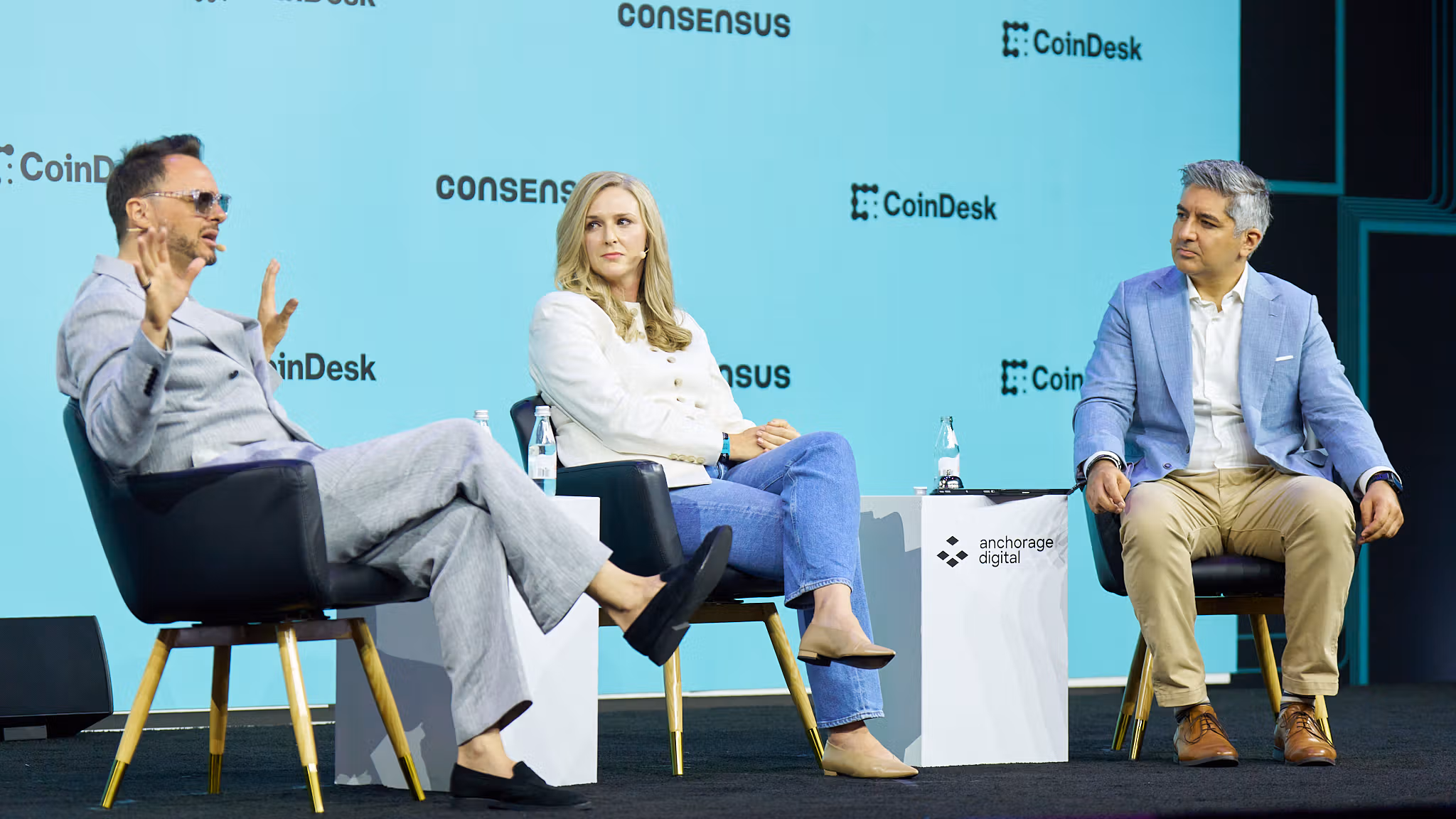 Tim Grant, CEO of Deus X Capital (left) and Lindsey Einhaus, head of strategy and operations of Bridge (middle) on stage at Consensus 2026 in Miami (CoinDesk)